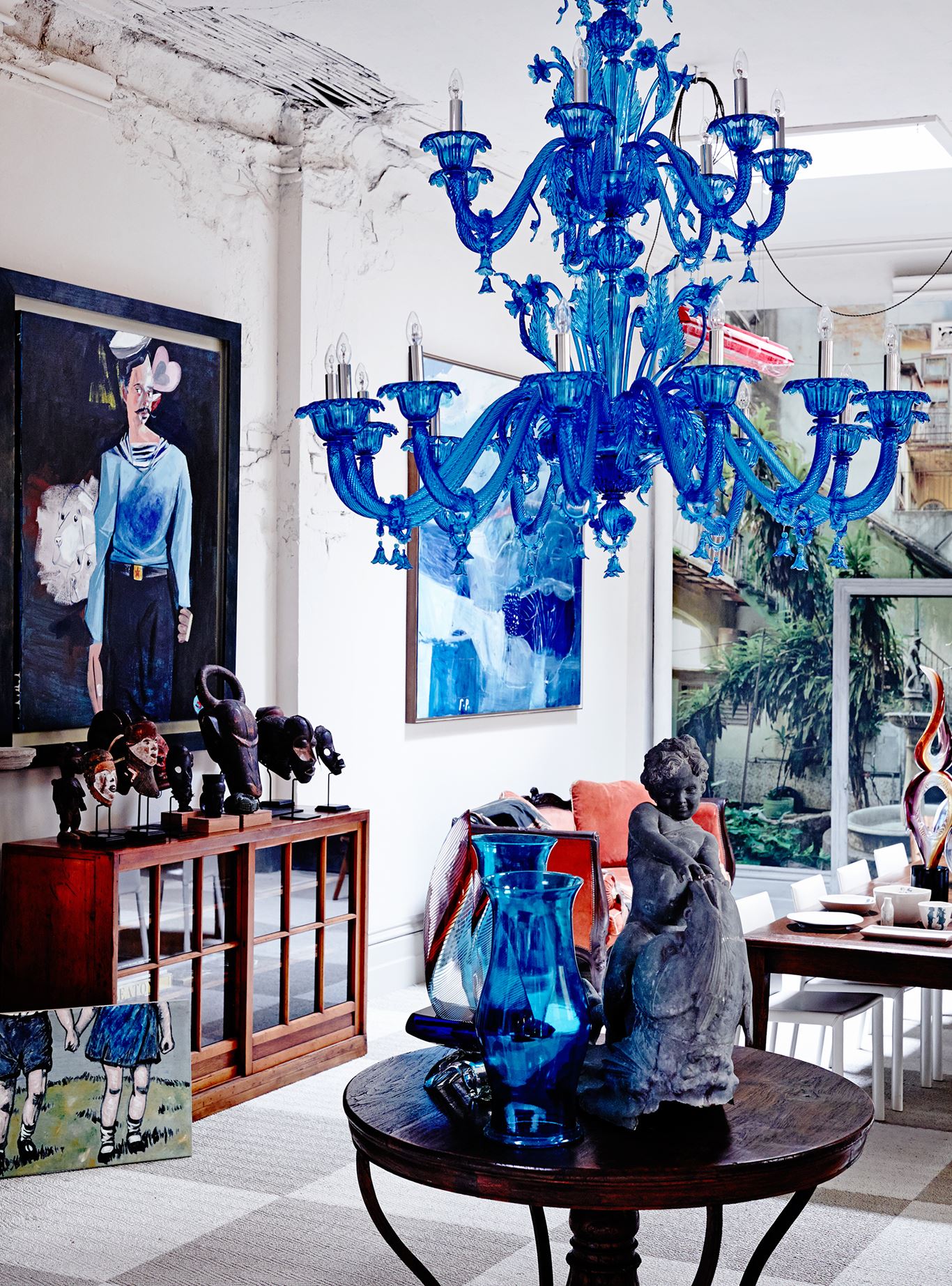 A blue Murano glass chandelier, mid-century sculptures from Ghana, a Japanese university cabinet and paintings by David Bromley (on floor), McLean Edwards and George Raftopoulos.