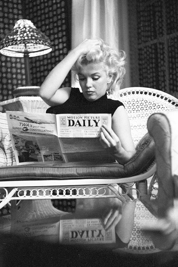 Marilyn Monroe reads the Motion Picture Daily newspaper while relaxing in her hotel room, 1955.