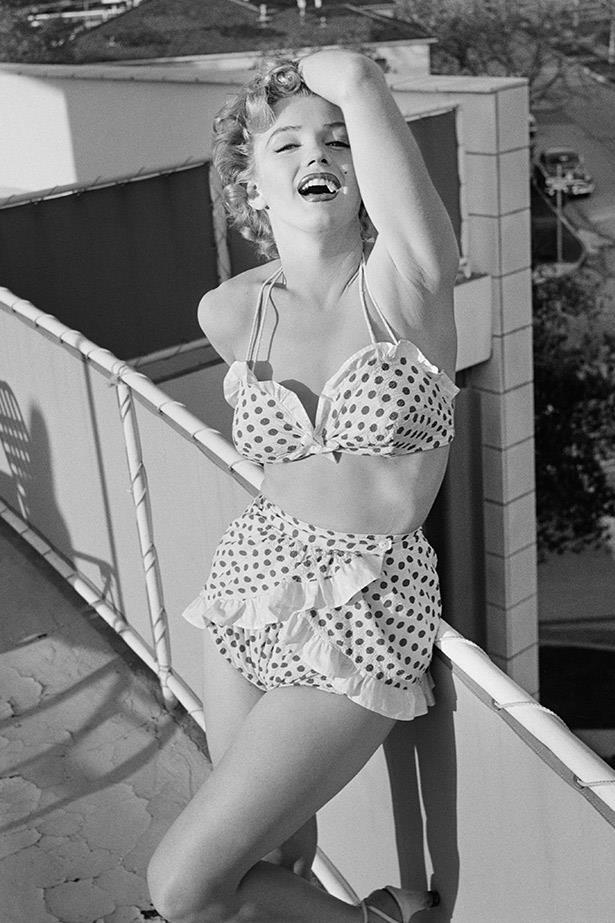Before she was a star, Marilyn Monroe (or Norma Jeane) was a successful model. Here she shows off her bombshell poses in a frilled bikini in LA in the early 50s.