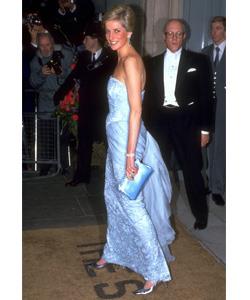 Diana, Princess of Wales, wearing one of her classic full-length strapless gowns with matching clutch purse.
