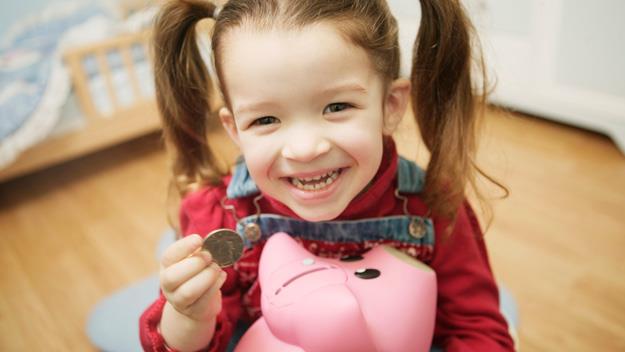 Little girl with coin and piggy bank 