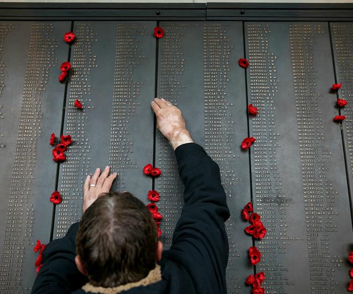 A man places a poppy against his grandfather's name in Canberra, Australia.
