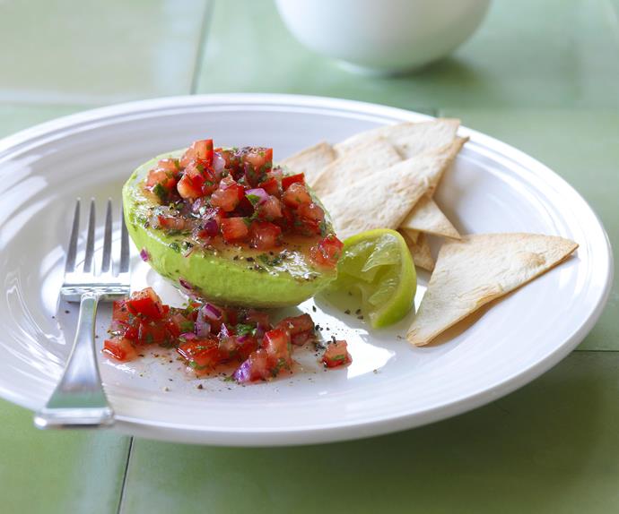 Half an avocado filled with tomato and onion salsa.