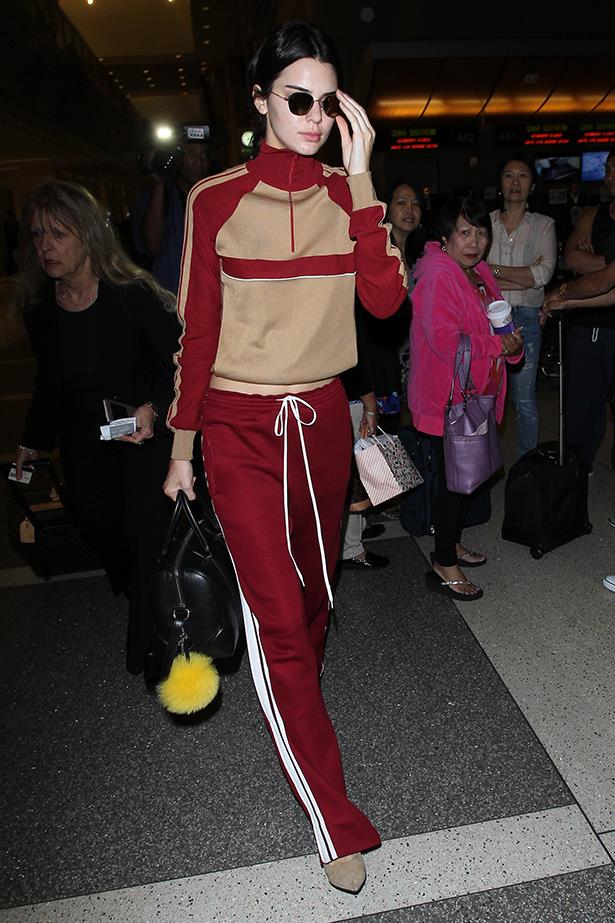 Kendall robed up in this mustard and red tracksuit when she flew out of LA last night. Peep that yellow pom-pom, too.