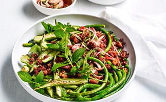 A round white dish with a stir-fry of pork mince, snake beans and sliced okra, topped with mint sprigs.