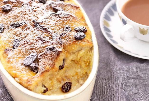 A white oval dish of bread and butter pudding on a grey linen tablecloth.