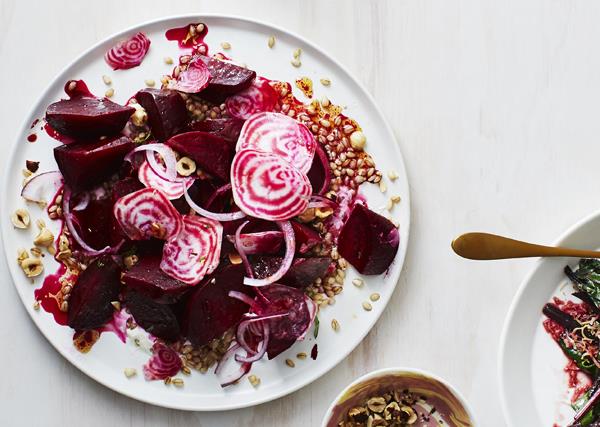On a white plate, a salad of beetroot wedges, barley and thinly sliced pink-and-white striped beetroot. 