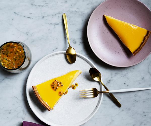 A triangular slice of passionfruit on a white plate, and another on a purple plate.