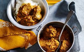 Two bowls with slow-cooked beef rendang curry, on a golden square tray with mustard-yellow and blue napkins.
