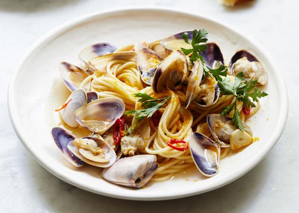 A white plate holding spaghetti, clams, chilli and flat-leaf parsley.