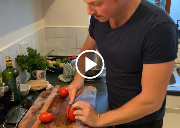 Toby Wilson chopping a tomato on a cutting board.