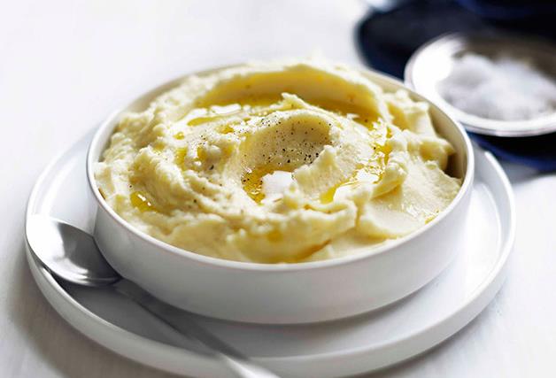 A white dish holding creamy mashed potato, with a grind of black pepper on top.