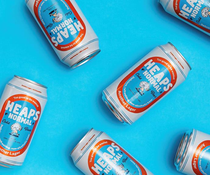 Cans of Heaps Normal's new beer, Another Lager, set against a light blue background. 