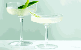 Two glasses of Ari Onassis cocktail garnished with two long slices of baby cucumber each