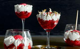 Different shaped glasses filled with red fruit and cream trifle