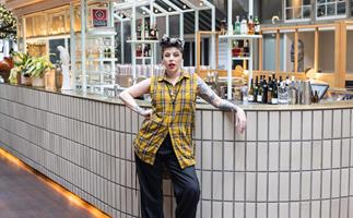 Chef Shannon Martinez in yellow top and black pants posing infront of white central bar