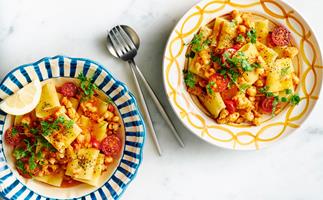Two colourful bowls dilled with paccheri pasta, tomatoes, prawns and herbs