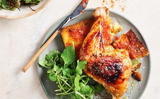 Roast chicken leg on top of bread with tomato-based sauce and side salad