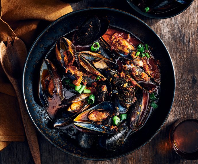 XO mussels stir-fried in XO sauce  in a dark ceramic bowl
