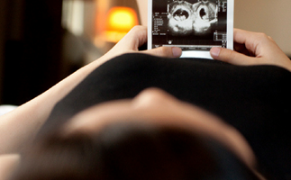 Woman on bed holding ultrasound image