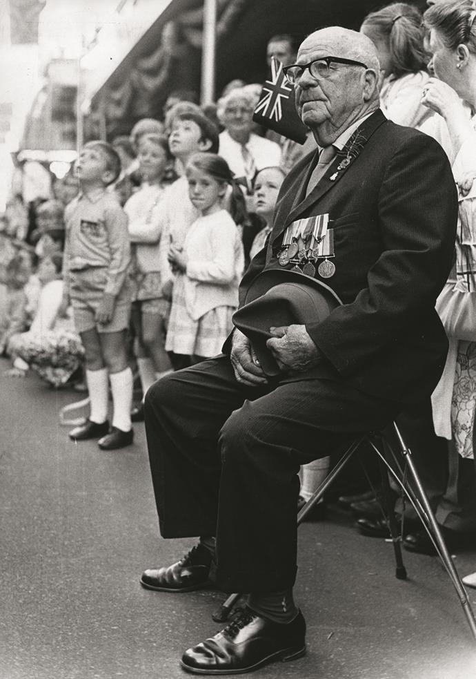 An old man removes his hat in respect as the parade passes him.
