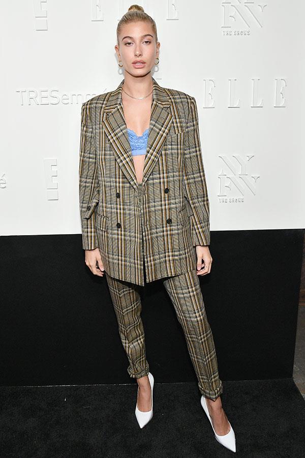 Hailey Baldwin donned an oversized plaid pant suit to the New York fashion week Kickoff Party, complete with crisp white pumps, a contrasting Lonely bralette and slicked back hair.