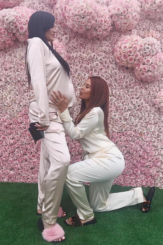 Yris Palmer knees down to air-kiss Kylie Jenner's baby bump at her baby shower, whilst the expectant mum holds on to a handful of polaroids.