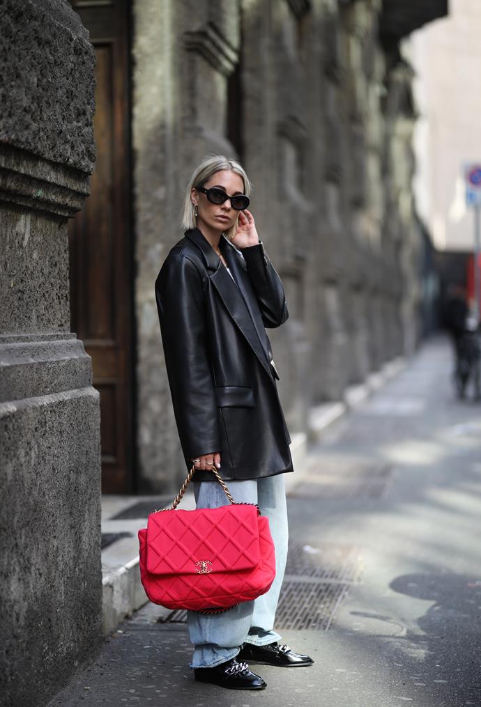 **Statement accessories** <br><br>
In Milan, we saw It-girls pairing their simple, wearable looks with accessories to do all the talking—i.e., this attendee wearing Chanel's covetable '19' handbag in a bright red hue.