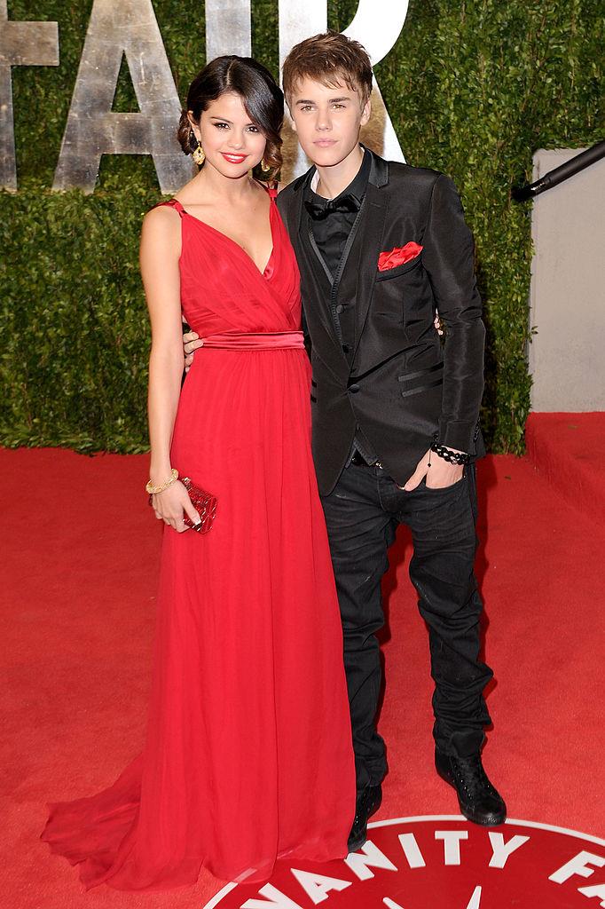 **Selena Gomez & Justin Bieber, 2011**
<br><br>
Making a red carpet debut, Gomez chose a stunning red Dolce & Gabbana gown for her red carpet look. Of course, Bieber tied the look together with a matching pocket square.