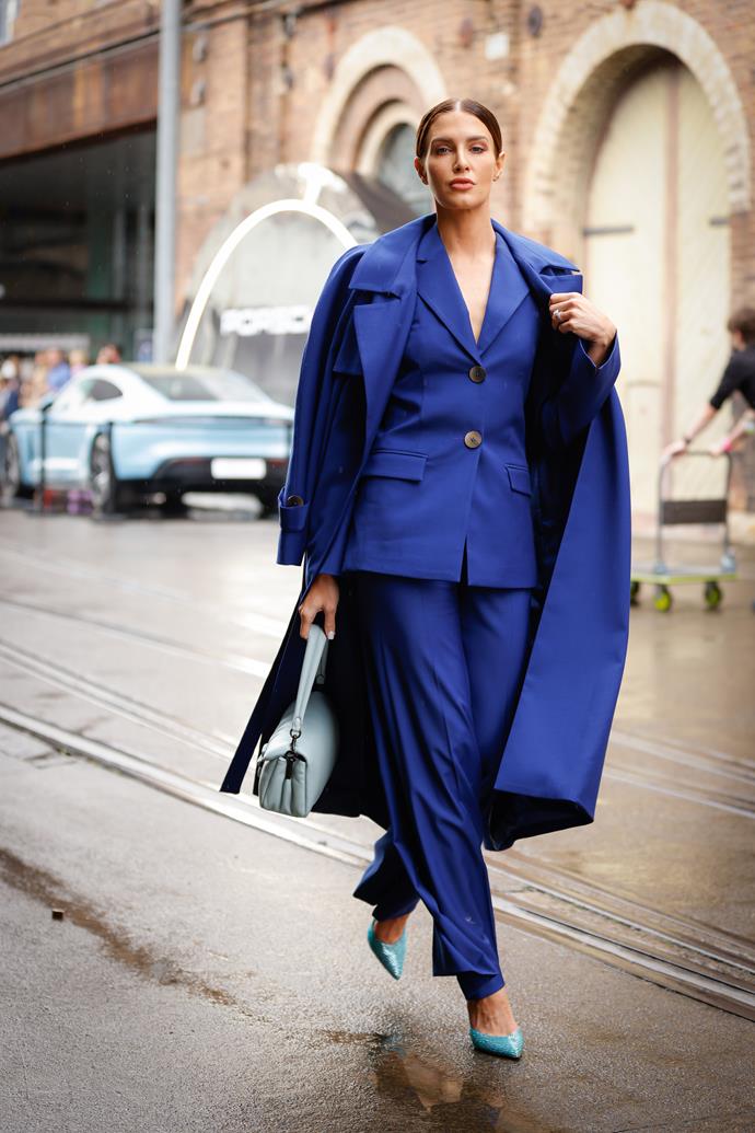 Erin Holland wears a blue, Bianca Spencer suit and matching trench coat, paired with Steven Madden heels and a Coach handbag.
<br><br>
*Image credit: Getty Images.*