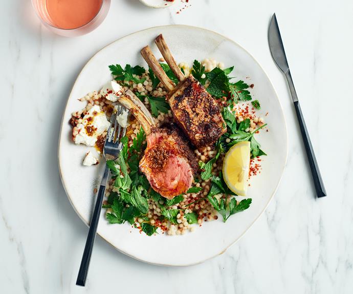 Aerial image of two lamb cutlets on top of a couscous salad with lemon and herbs.