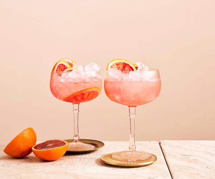 Two coup glasses filled with light pink cocktails and topped with slices of ruby grapefruit.