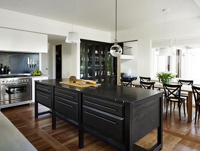 Walls were shifted in the kitchen to accommodate a cool room, walk-in pantry and a glass-fronted storage wall, the only structural changes in the house. When they selected the colour of the classic marble for the benchtop, designer Sarah Davidson told the owner it’s either “the little black dress or the little white dress, both are timeless”. The owner chose the black, echoed in the splashback and behind the china cabinet, “so it’s not a flat wall, to give it life and make it inclusive and warm,” says Sarah. 

Island **bench** in Nero Marquina marble from [SNB Stone](http://www.snb-stone.com/|target="_blank"), with American oak **joinery** stained black. Hanging **fishbowl** bought in New York. Flos Romeo Moon S1 **pendant light** and S2 **pendant light** over table, both from [Euroluce](http://euroluce.com.au/|target="_blank"). Essay **dining table** from [Cult](http://www.cultdesign.com.au/|target="_blank"). **Dining chairs** from [Domo](http://www.domo.com.au/|target="_blank").