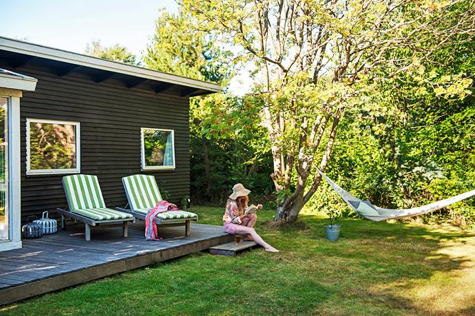 Homeowner Cecilia relaxes in the garden, where old birch trees offer plenty of shade on a hot summer's day.