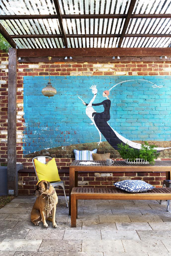 Ben constructed the pergola from recycled jarrah posts and beams; clear sheeting on its roof allows winter light into the house. Carla painted the vintage *Vogue* mural on the recycled brick wall to match the colours and tones of the interior.