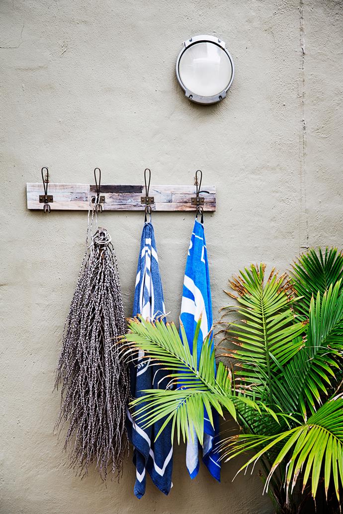 A rustic rack hung at the back door is ideal for the kids to stash wet towels. Natural items such as dried plants and driftwood bring the beach to the backyard.