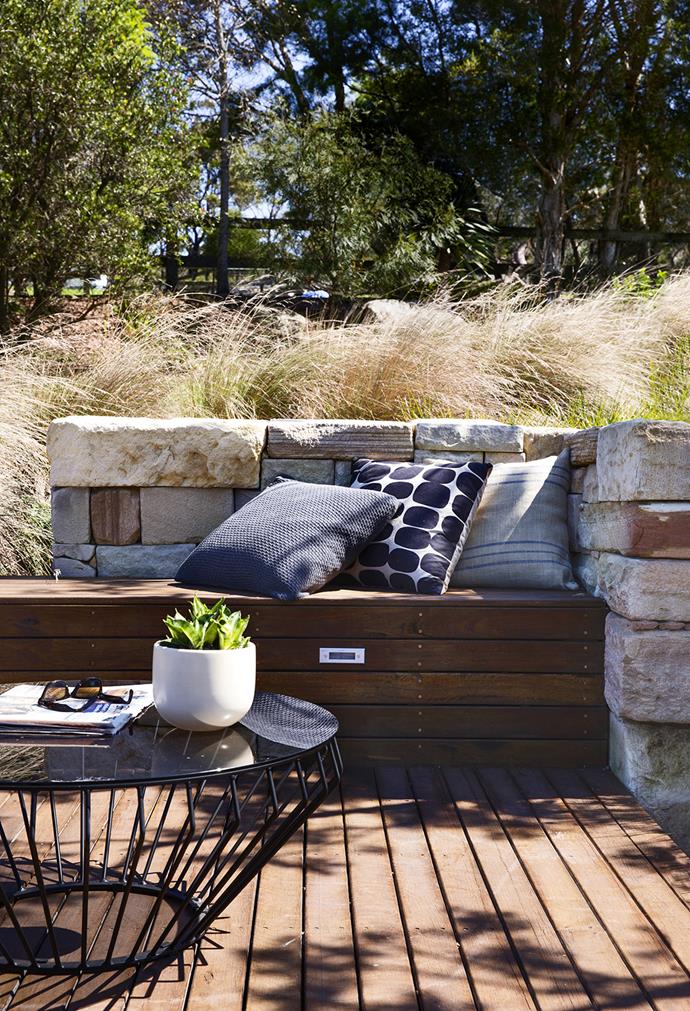 This drystone wall is built from sandstone, the majority of it taken from the property and the remainder matched from a recycled-stone supplier. The bench and decking is built from sustainable spotted gum. The sandy coloured grass fringing the wall is Poa 'Eskdale'. 

**Cushions** from [The Design Hunter](http://www.thedesignhunter.com.au/|target="_blank"). **Table** from [Tait](http://www.madebytait.com.au/|target="_blank"). **Pot** from [Garden Life](http://gardenlife.com.au/|target="_blank").