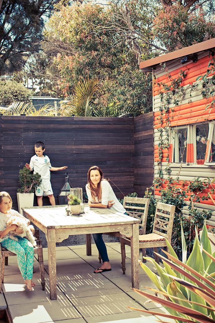 The family gather at their rustic timber outdoor setting from eBay. “I love that it’s all grey and weathered,” Priscilla says. The couple painted the shed in bold red and taupe stripes to make it a feature. “It took a lot of masking tape and patience, but it’s well worth it!”