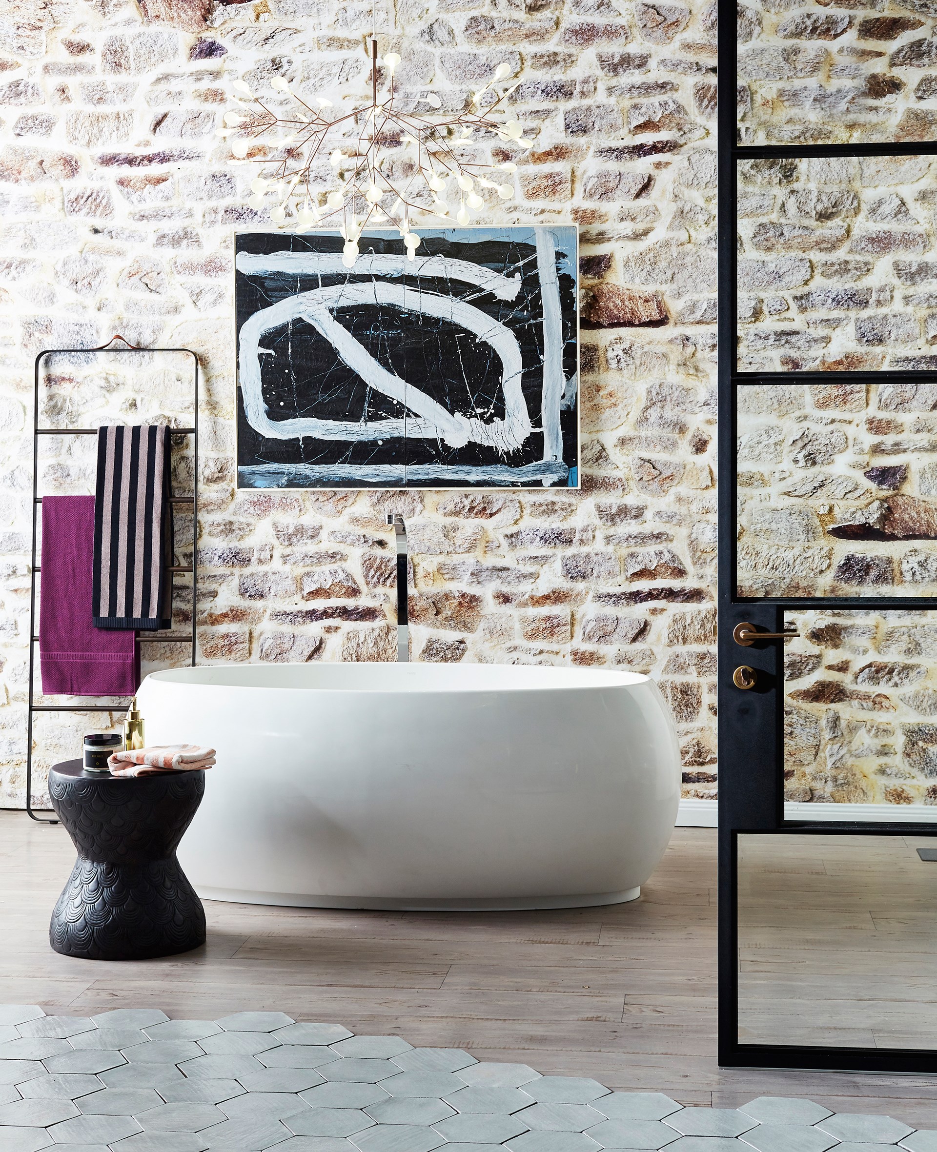 **Art attack.** Hexagonal tiling, an exposed brick wall and contemporary artwork all make great talking points in this light-filled space with a free-standing, luxurious tub. *Photo: John Paul Urizar / bauersyndication.com.au*