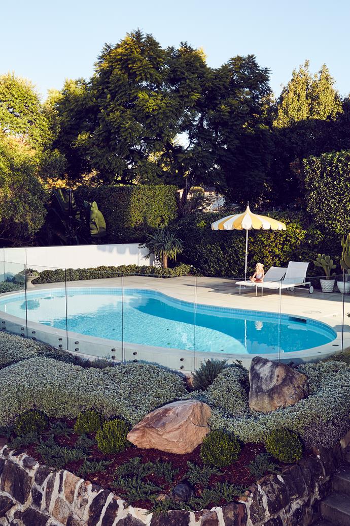 With its jellybean shaped pool and layered planting, this garden, attached to an [original 1950s home](https://www.homestolove.com.au/comedian-tim-ross-original-1950s-home-3980|target="_blank"), gives off some serious holiday vibes. Though it looks grown in and like it completely belongs to the property, this landscaped yard was actually a more recent addition.