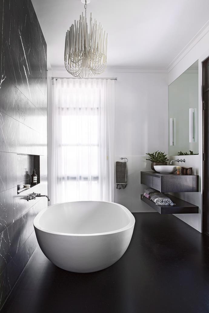 **Light and dark.** A freestanding bath with luxurious rounded edges, combined with a contemporary chandelier and monochrome palette make for a truly show-stopping bathroom space. *Photo: Angelita Bonetti / bauersyndication.com.au*