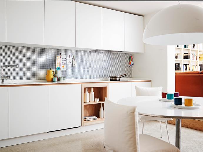 The kitchen was designed by the couple’s architecture firm; simple white cabinetry is broken up with a timber box shelf and trim. Silver tapware is the finishing touch.