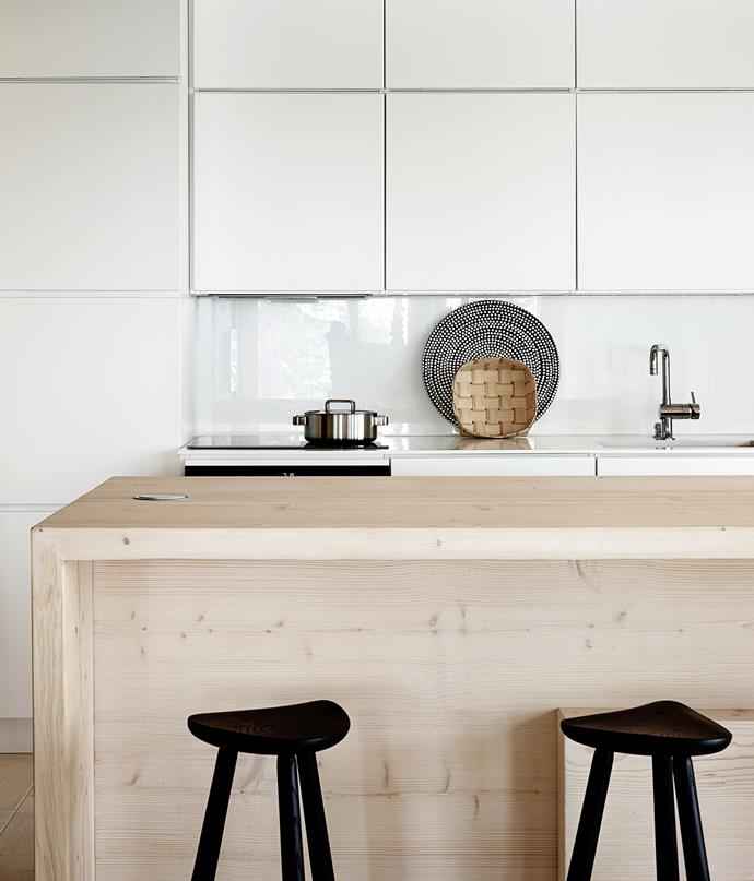 The open-plan kitchen is pared-down and simple, with smooth, handleless cabinets. The same timber that was used for the floors was used for the large kitchen island for a simple, unifying look.