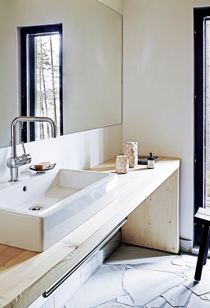 A large bathroom mirror, fixed to the wall, doubles the space and reflects the window view.