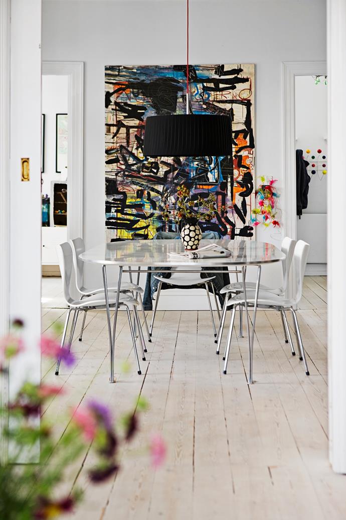 The simplicity of the dining setting allows the striking, colourful artwork to take centre stage.