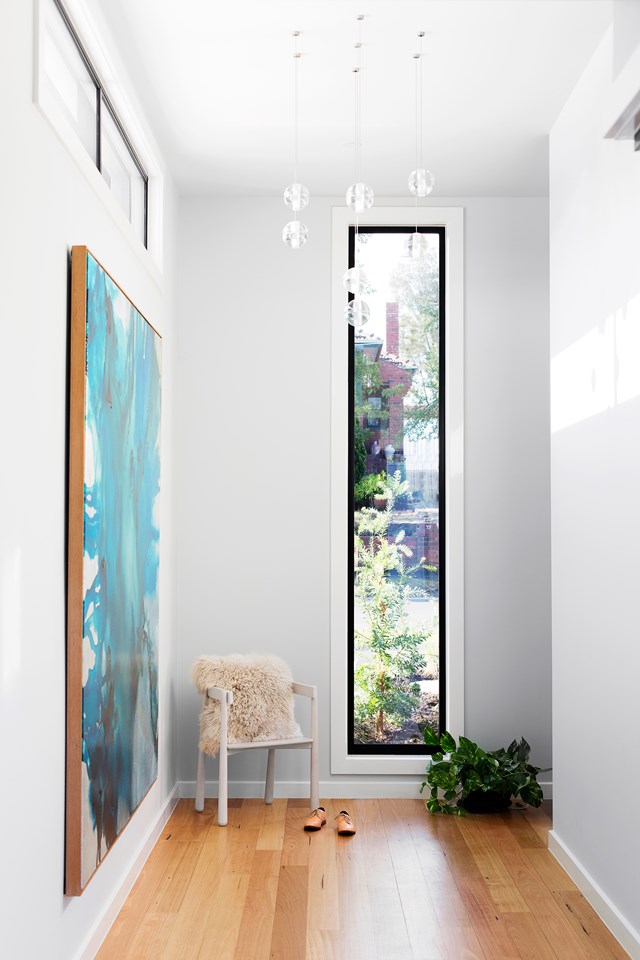 Rectilinear windows frame views of greenery, balanced by a vibrant abstract painting by Tessa Dodds. Photographer: Martina Gemmola