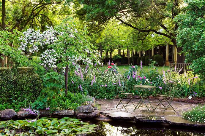 The tranquil spot by the pond is surrounded by beds filled with foxgloves and poppies. Waterlilies and white-blossomed crabapple add to the display.