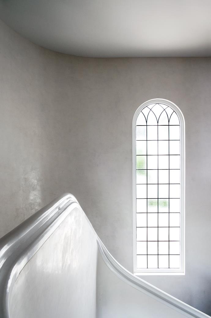 A multi-paned arched window illuminates the stair.