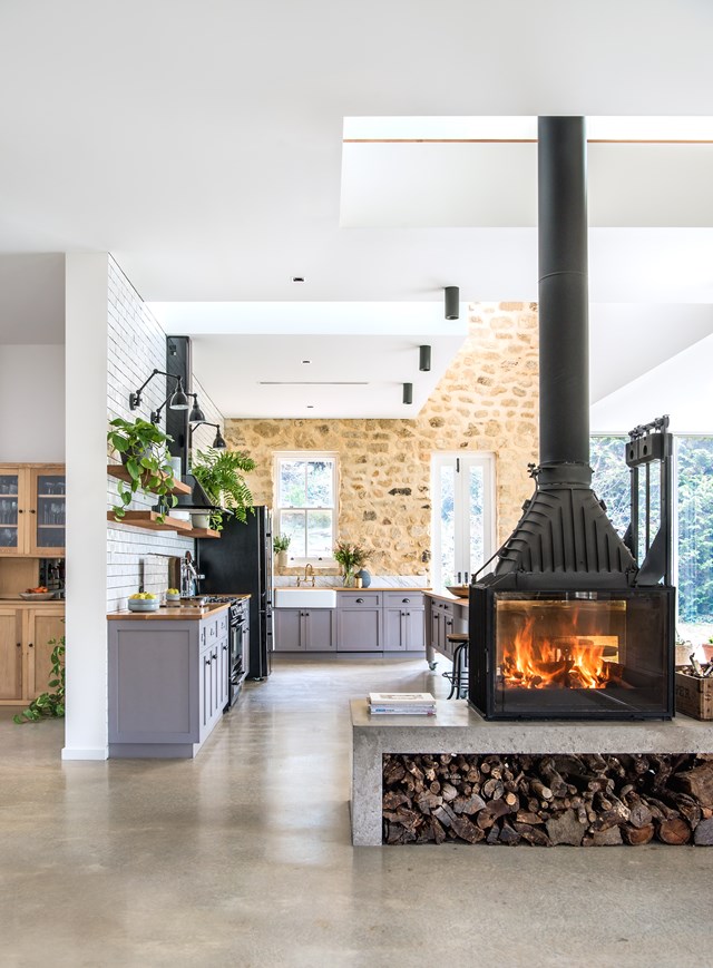 This double-sided fireplace is as beautiful as it is functional, providing warmth to the kitchen and living areas, while housing a stack of chopped wood in the cement niche below. Linda, the owner of this [country-style kitchen](https://www.homestolove.com.au/country-style-kitchen-by-georgie-shepherd-interior-design-5728|target="_blank") said she "wanted it to look like an old barn with a contemporary fit-out inside."