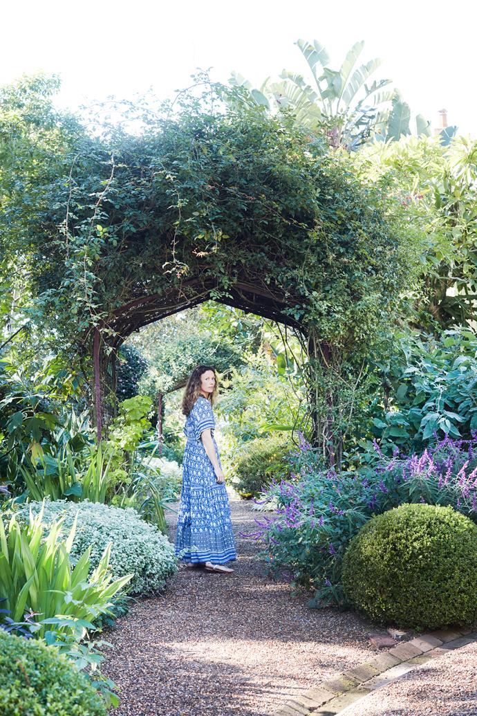 Anna walks through a bower surrounded by trees and plants tended by the van der Gardners, with regular help from Pepo Botanic Design.
